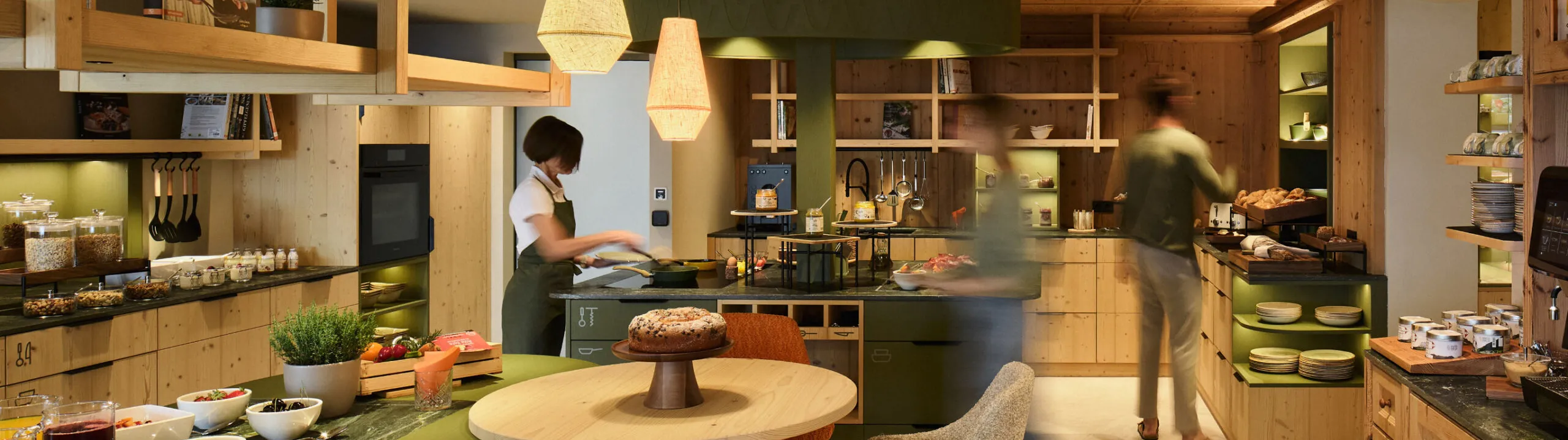 Ein liebevoll angerichtetes Frühstücksbuffet in der Community Kitchen des AUI Hotels, mit einem Tisch mit Stühlen und verschiedenen Speiseangeboten