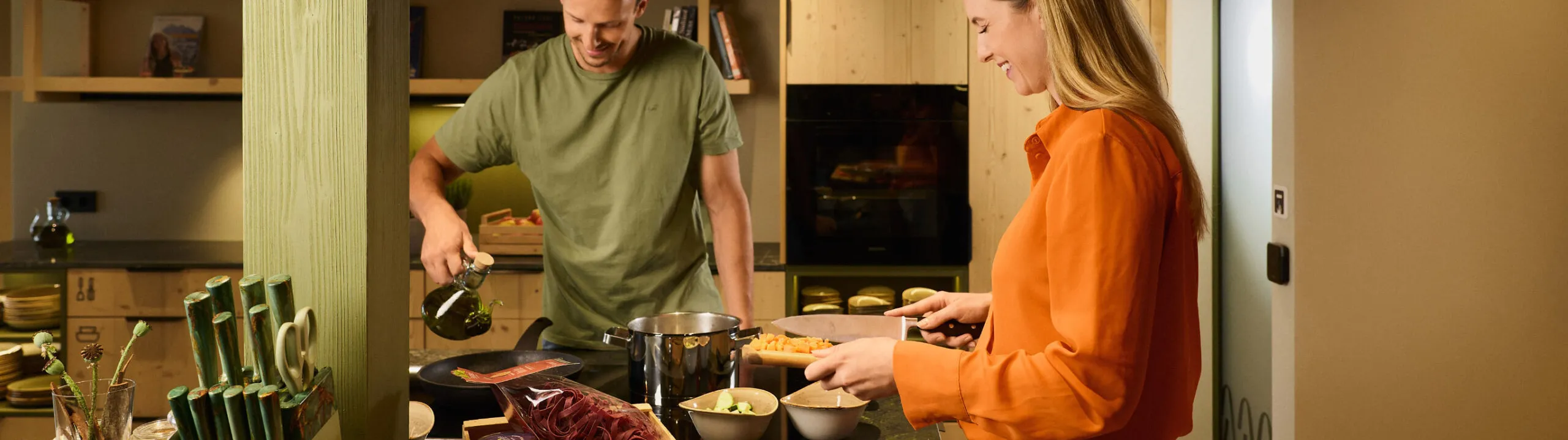 In der Gemeinschaftsküche des AUI Hotels bereiten ein Mann und eine Frau gemeinsam das Abendessen zu und erleben dabei einen besonderen Moment des gemeinsamen Kochens.