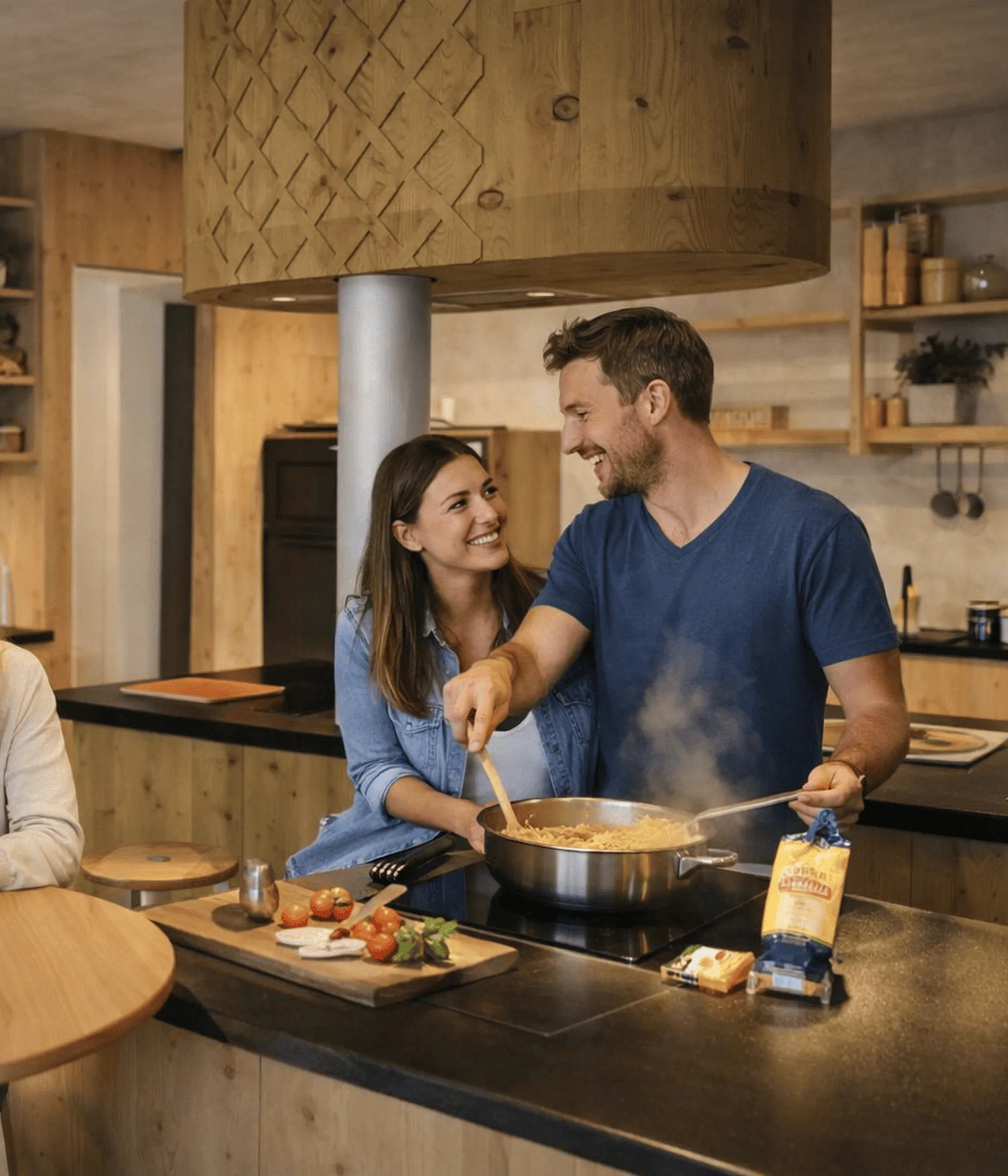 A cheerful group of four friends enjoy cooking in a warm, rustic kitchen. Two hold glasses of red wine, while another stirs pasta on the stove.