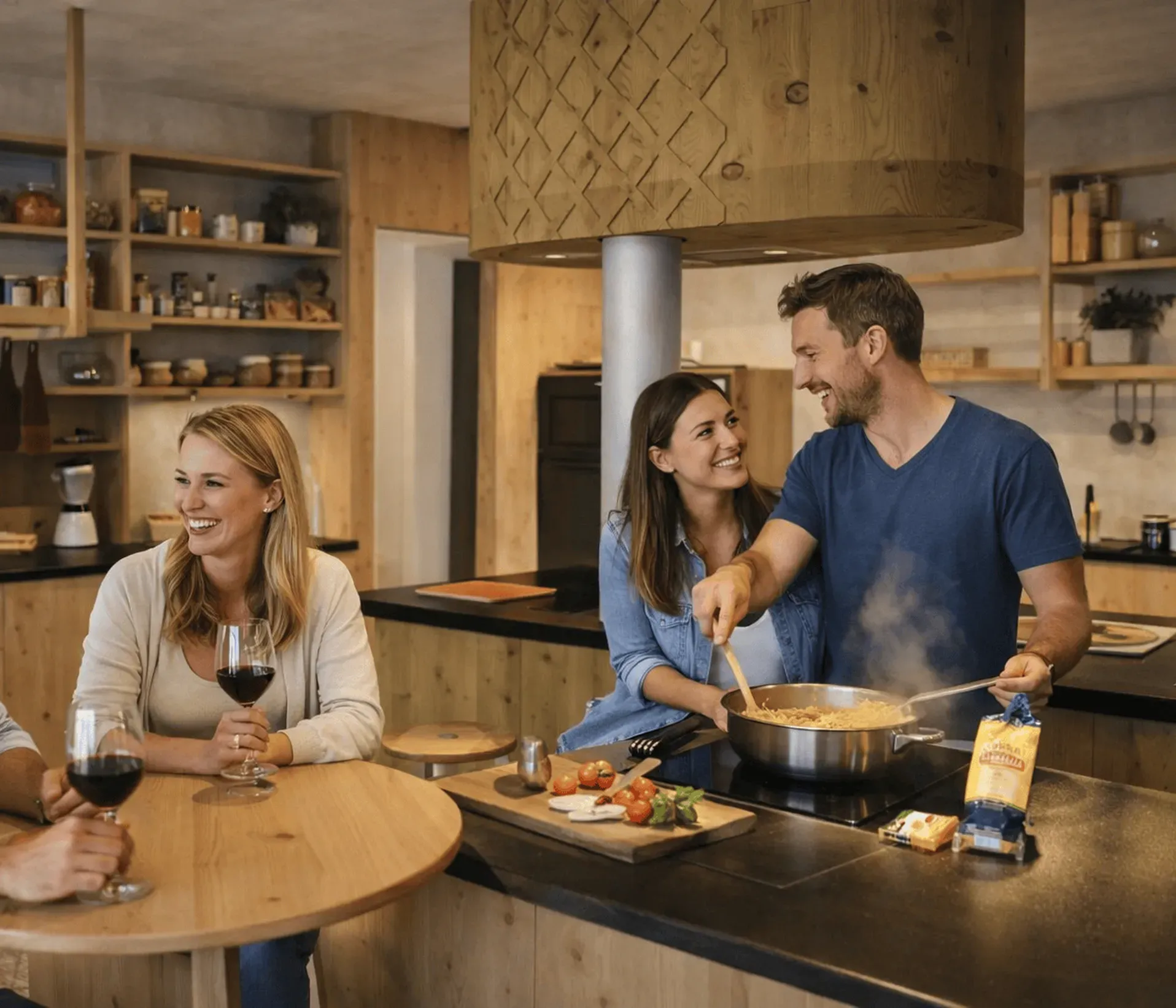 A cheerful group of four friends enjoy cooking in a warm, rustic kitchen. Two hold glasses of red wine, while another stirs pasta on the stove.