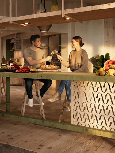 Couples socialize in a warm, inviting kitchen with wood accents. They prepare food, share drinks, and enjoy a cozy, intimate atmosphere filled with conversation.