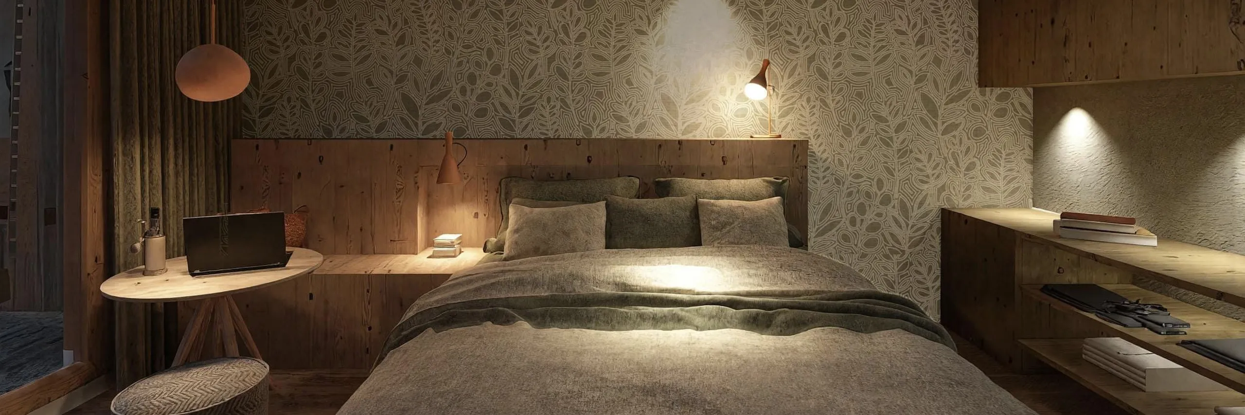 Cozy bedroom with a floral accent wall, soft lighting, and wooden furniture. A bed with gray bedding, laptop on a small table, and ambient warmth.