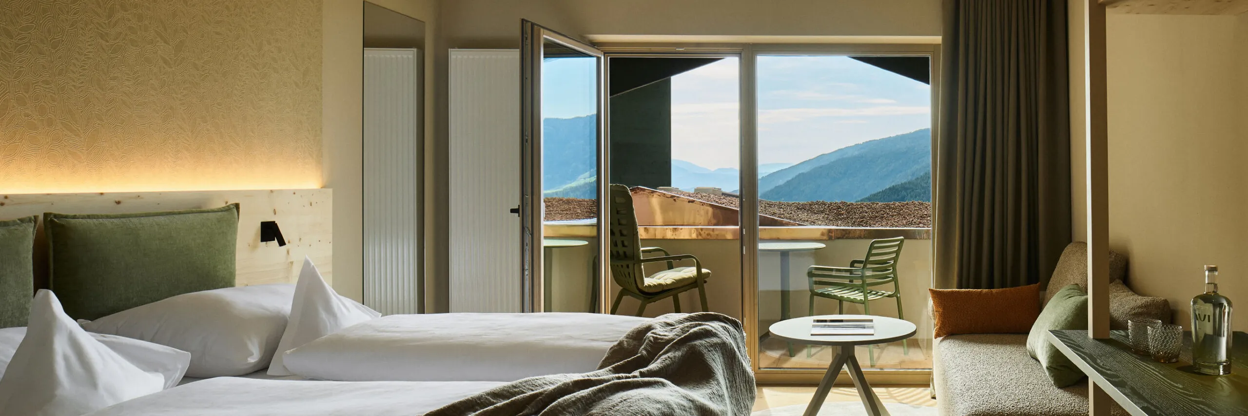 Zimmer im AUI Hotel mit Doppelbett, Sofa und einem malerischen Blick auf die Berge aus dem Fenster.