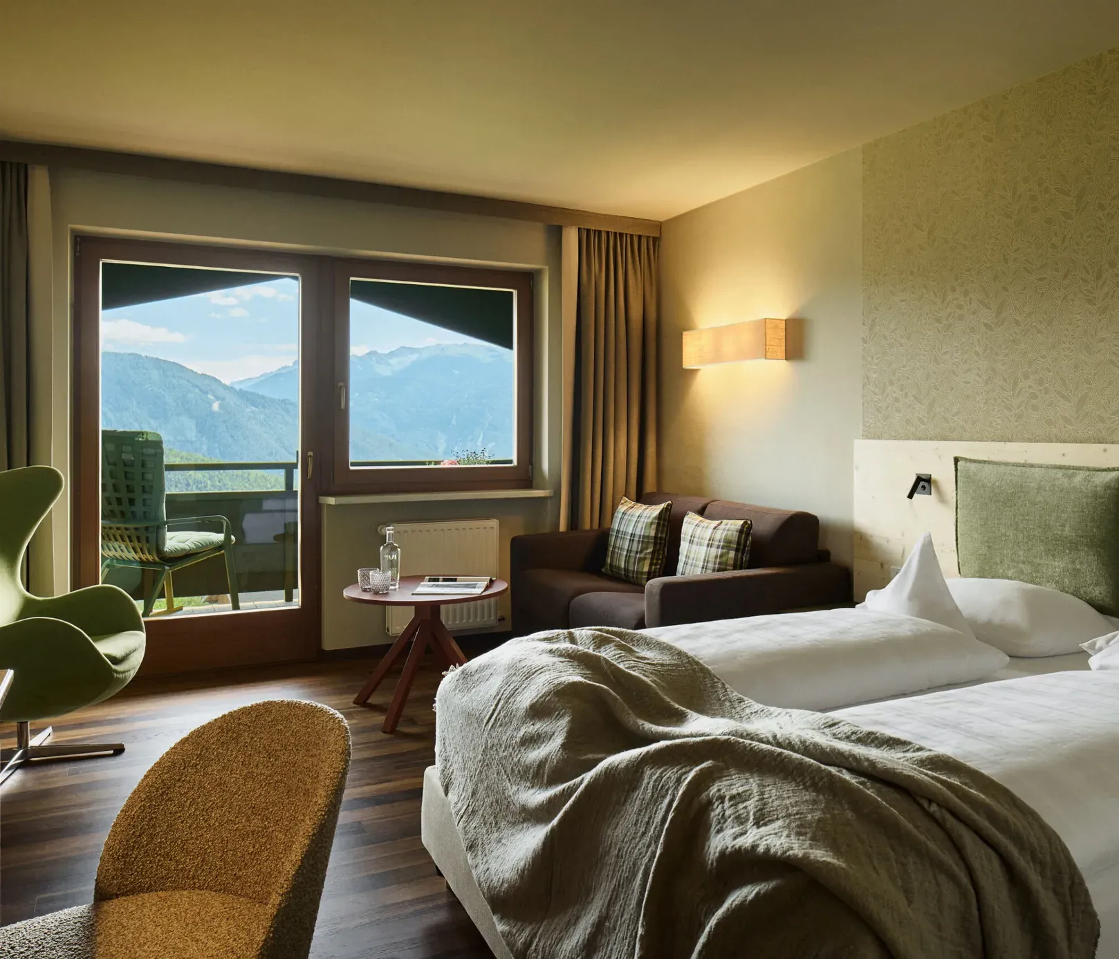 Gemütlich eingerichtetes Schlafzimmer im AUI Hotel mit Bett, Sessel, Fernseher und Fenster, das einen komfortablen und einladenden Raum schafft.