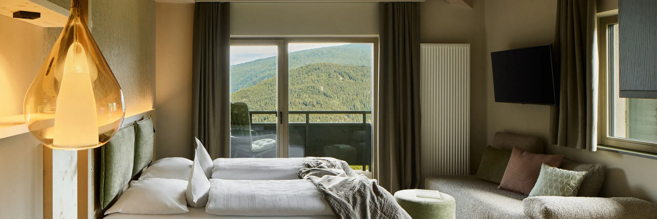 Camera da letto elegante di un appartamento AUI con un comodo letto, televisore e tavolo, che crea un’atmosfera accogliente.
