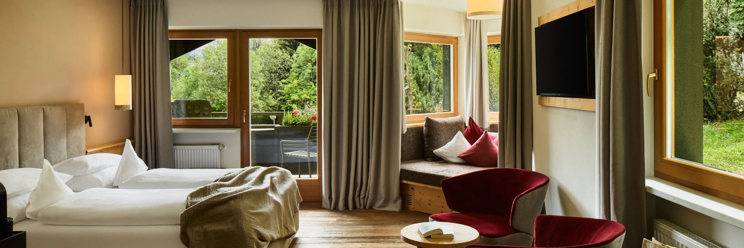 Stilvoll eingerichtete Suite im AUI Hotel mit Bett, Sessel und Fernseher, gestaltet für den Komfort der Gäste.