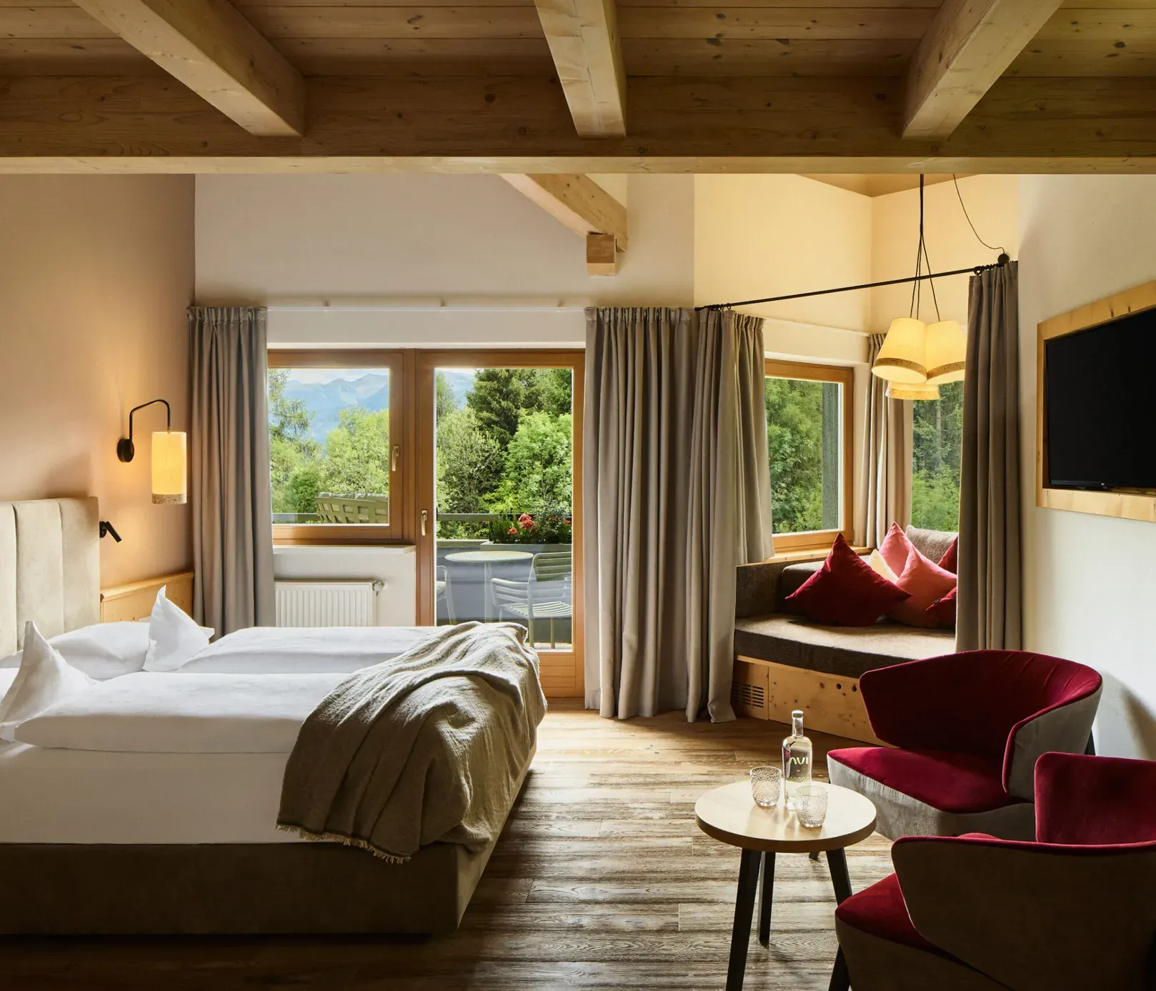 AUI Suite mit Bett, Sessel und Fenster mit einem malerischen Blick auf die Berge.